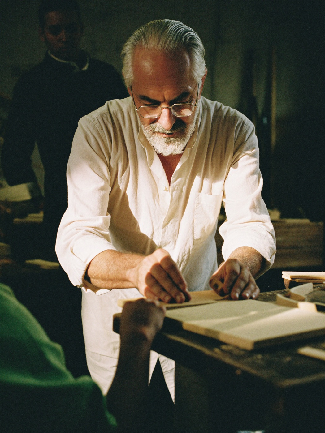 Le mani di un maestro artigiano guidano quelle di un giovane apprendista al banco di lavoro